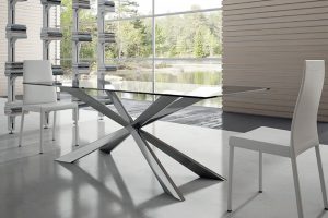 Tavolo fisso con piano vetro o piano scortecciato in legno con basamento laccato.